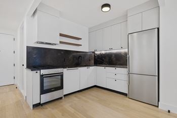 Contemporary kitchen with stainless steel appliances and light wood flooring